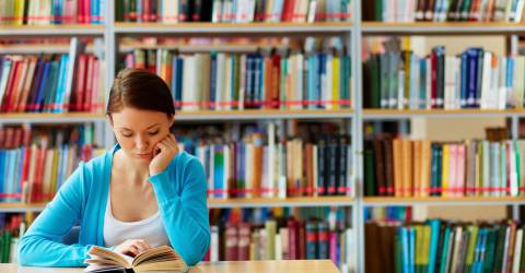 Student zit telezen in bibliotheek 